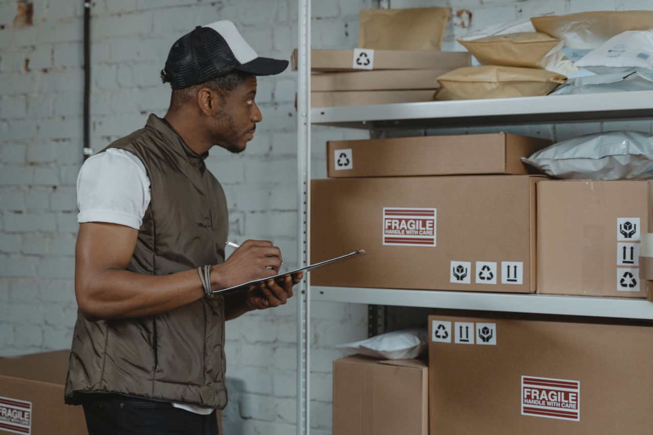 A storekeeper checks boxes on the shelves against a list